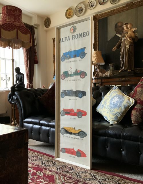 fig 1. A long vertical glazed poster displaying six illustrated historical Alfa Romeo motor cars arranged chronologically from 1910 to 1950 on a cream paper background inside a white frame.