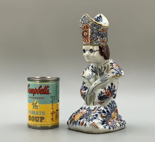 fig 1. An 18th-century Dutch Delftware ceramic candlestick formed as a kneeling bishop in patterned robes and a mitre decorated with polychrome glazes.
