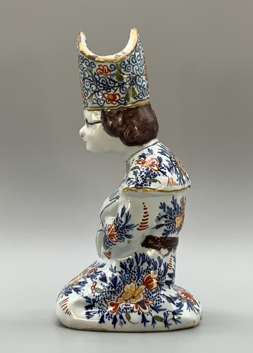 fig 4. An 18th-century Dutch Delftware ceramic candlestick formed as a kneeling bishop in patterned robes and a mitre decorated with polychrome glazes.