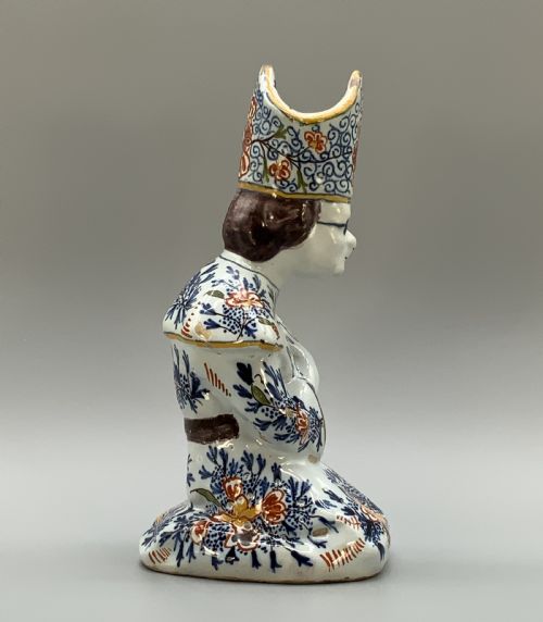 fig 5. An 18th-century Dutch Delftware ceramic candlestick formed as a kneeling bishop in patterned robes and a mitre decorated with polychrome glazes.