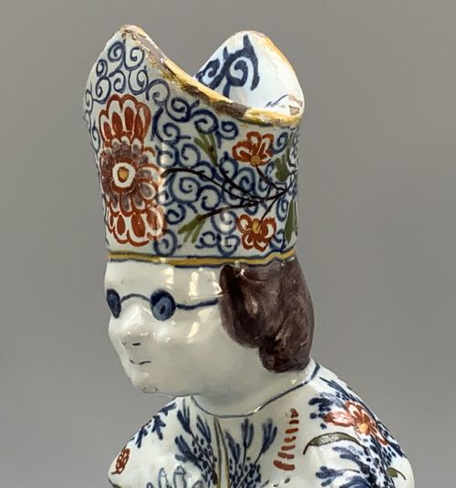 fig 7. An 18th-century Dutch Delftware ceramic candlestick formed as a kneeling bishop in patterned robes and a mitre decorated with polychrome glazes.