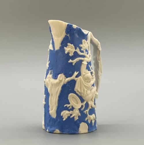 fig 3. A Victorian blue and white Parian ware jug featuring a textured cobalt blue ground with raised white relief figures climbing a tree and a moulded branch handle.