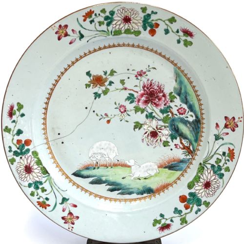 fig 2. A large circular Chinese export porcelain charger plate hand-painted with famille rose floral motifs, rockwork, and two white sheep on a pale background.