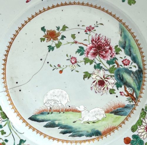 fig 4. A large circular Chinese export porcelain charger plate hand-painted with famille rose floral motifs, rockwork, and two white sheep on a pale background.
