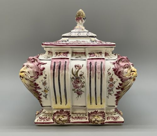 fig 4. An antique French faience covered soup tureen featuring hand-painted pastoral scenes in manganese purple, moulded lion mask side handles, and a stepped lid with a finial.