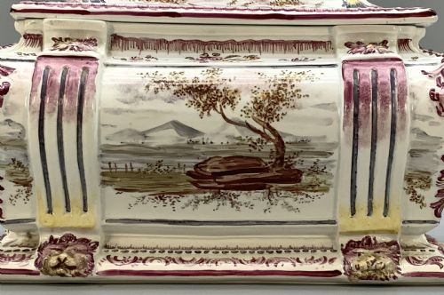 fig 6. An antique French faience covered soup tureen featuring hand-painted pastoral scenes in manganese purple, moulded lion mask side handles, and a stepped lid with a finial.