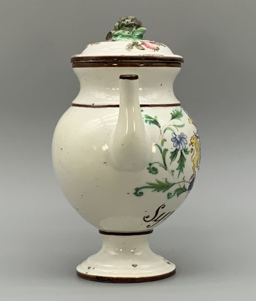 fig 5. An 18th-century Italian tin-glazed earthenware pharmacy wet drug jug with a spouted body, top handle, lid with sculpted finial, painted armorial crest, floral scrolls, and Latin text reading Syr Alth.
