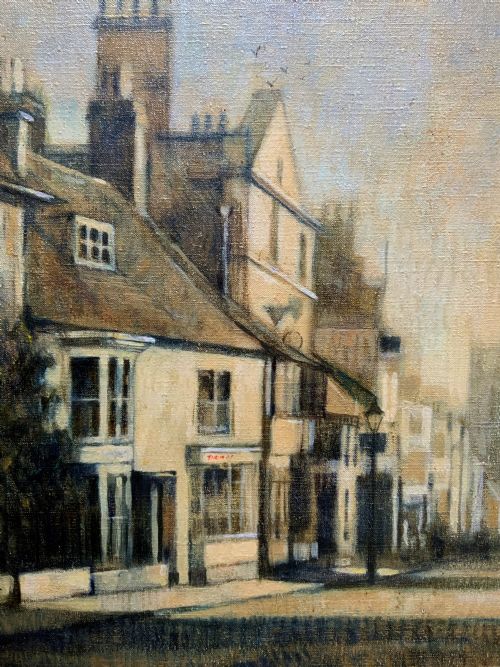 fig 4. A framed impressionist oil painting depicting a historic street scene with townhouses leading towards a church tower in muted brown, beige, and grey tones.