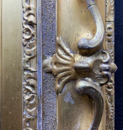 fig 6. An ornate 19th-century gold giltwood picture frame featuring intricate moulded gesso floral and shell embellishments around a central rectangular aperture.