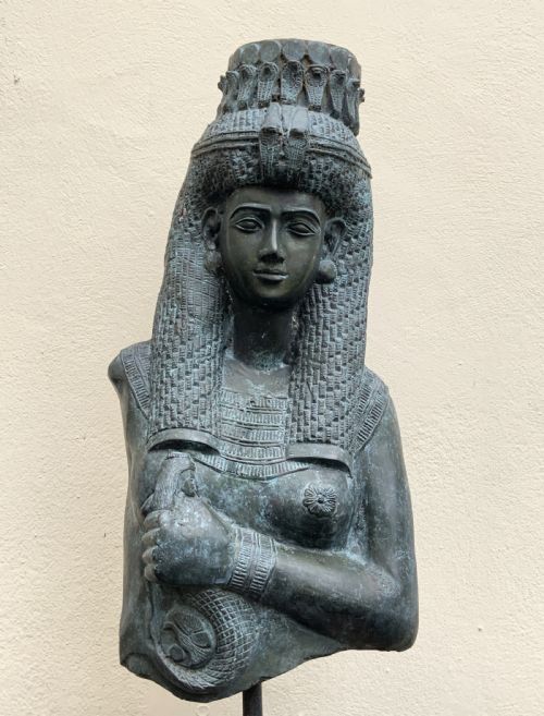 fig 6. A dark green patinated bronze bust of Cleopatra holding an asp, mounted on a rectangular pink marble base.
