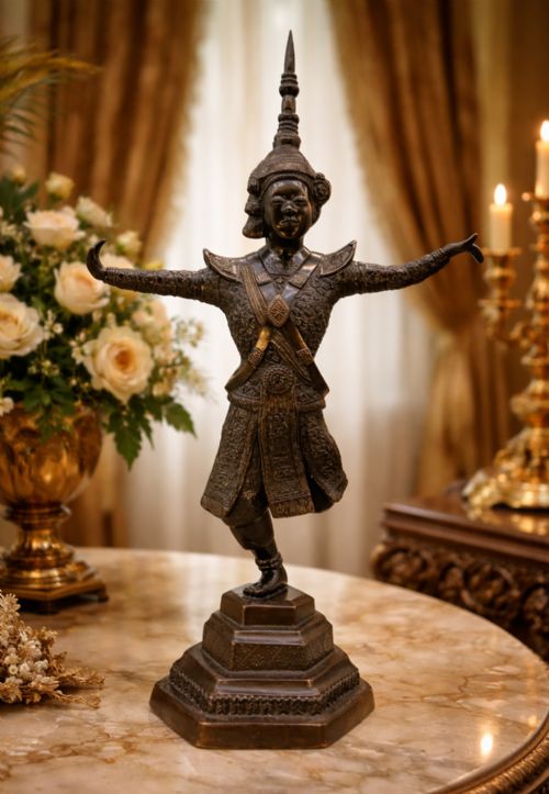 fig 1. A dark bronze sculpture depicting a classical court dancer in ceremonial attire with a tall spired headdress, balanced on one foot atop an octagonal stepped base.