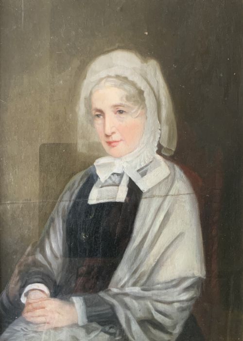 fig 3. A nineteenth-century oil portrait painting depicting a seated lady wearing a white lace bonnet and grey shawl, housed in a black ebonised frame with a pale inner slip.