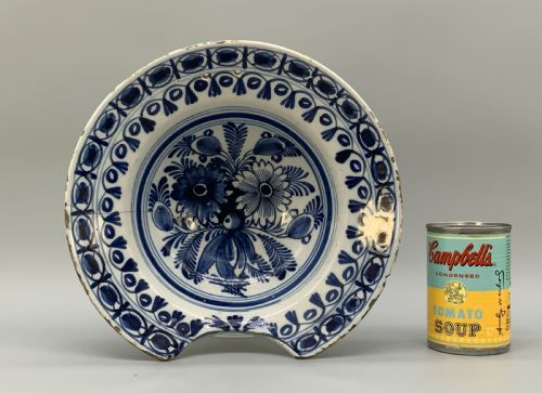 fig 2. An 18th-century blue and white Dutch Delftware barbers bowl featuring hand-painted floral motifs and a semi-circular rim notch.