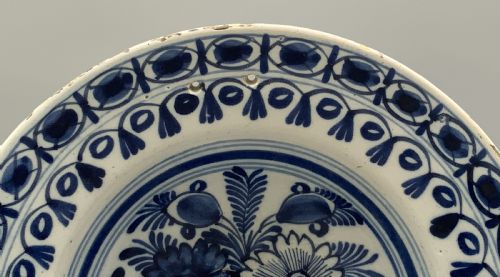 fig 4. An 18th-century blue and white Dutch Delftware barbers bowl featuring hand-painted floral motifs and a semi-circular rim notch.