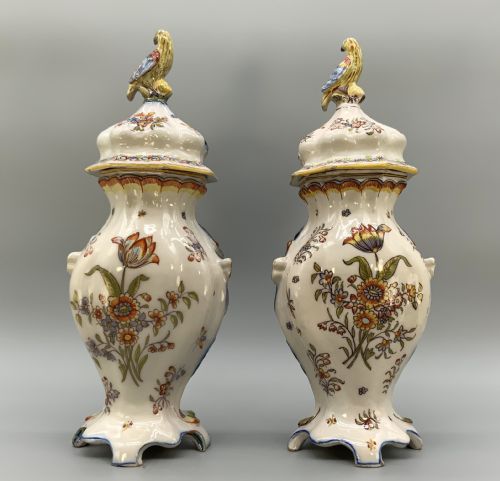 fig 3. A pair of ornate French faience lidded vases decorated with hand-painted polychrome florals, Rococo scrollwork moulding, and sculptural parrot finials.