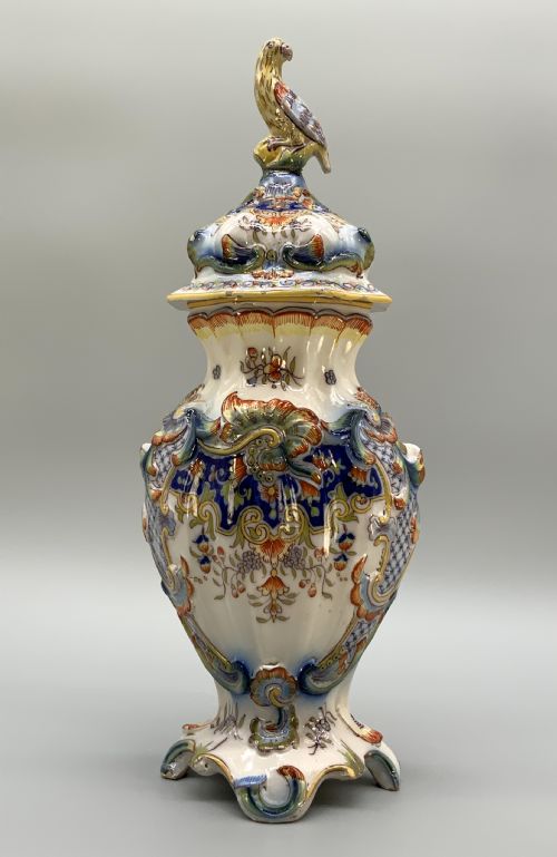 fig 4. A pair of ornate French faience lidded vases decorated with hand-painted polychrome florals, Rococo scrollwork moulding, and sculptural parrot finials.
