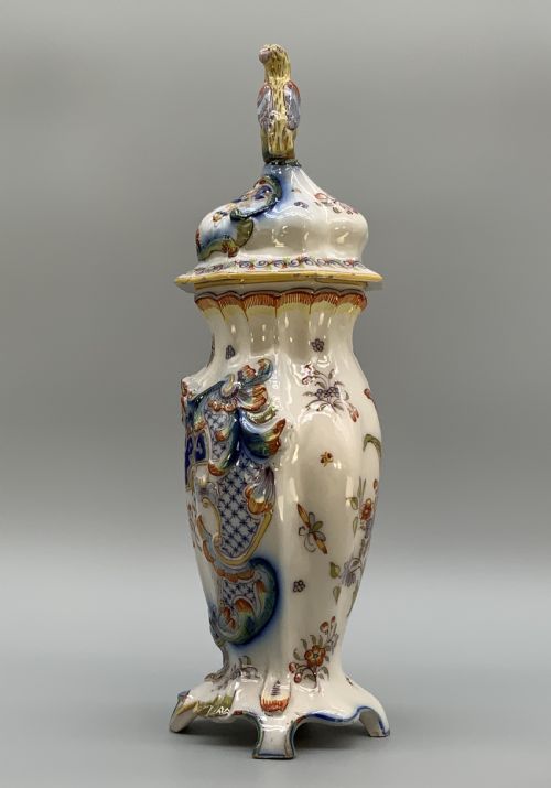 fig 5. A pair of ornate French faience lidded vases decorated with hand-painted polychrome florals, Rococo scrollwork moulding, and sculptural parrot finials.