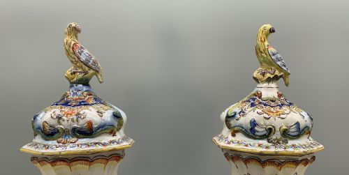 fig 6. A pair of ornate French faience lidded vases decorated with hand-painted polychrome florals, Rococo scrollwork moulding, and sculptural parrot finials.