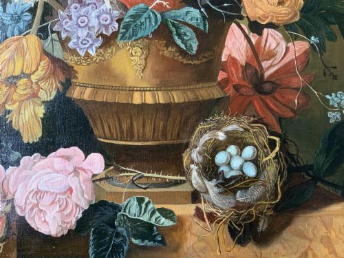 fig 6. A gilt-framed oil painting featuring a dense bouquet of colourful flowers in a classical urn alongside a birds nest with eggs.