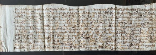 fig 2. A framed 17th-century handwritten vellum document featuring brown ink calligraphic script presented in an ornate dark wood frame.