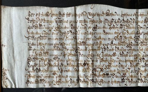 fig 3. A framed 17th-century handwritten vellum document featuring brown ink calligraphic script presented in an ornate dark wood frame.