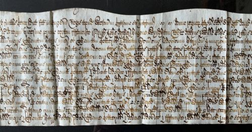 fig 4. A framed 17th-century handwritten vellum document featuring brown ink calligraphic script presented in an ornate dark wood frame.