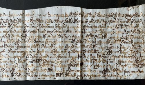 fig 5. A framed 17th-century handwritten vellum document featuring brown ink calligraphic script presented in an ornate dark wood frame.