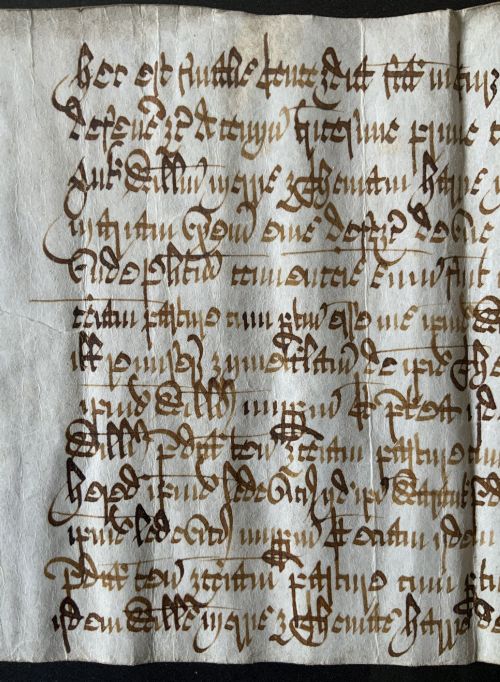 fig 7. A framed 17th-century handwritten vellum document featuring brown ink calligraphic script presented in an ornate dark wood frame.