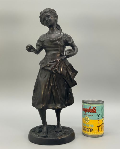 fig 2. An antique dark bronze sculpture of a young maiden wearing a draped apron dress, standing barefoot on a rounded integral base.