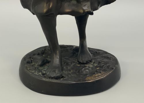 fig 5. An antique dark bronze sculpture of a young maiden wearing a draped apron dress, standing barefoot on a rounded integral base.