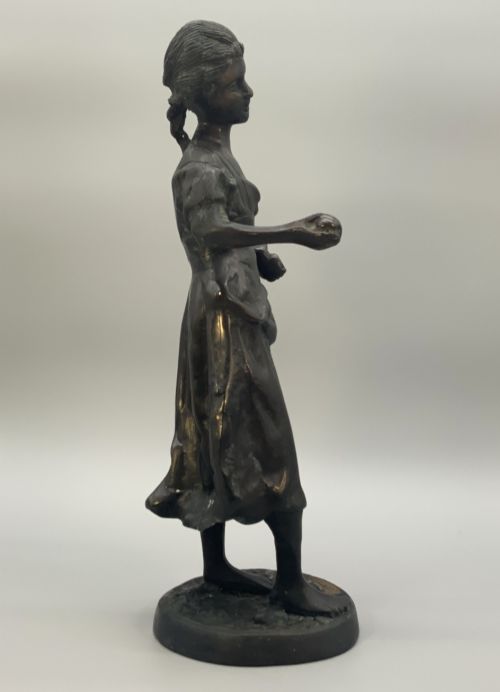 fig 8. An antique dark bronze sculpture of a young maiden wearing a draped apron dress, standing barefoot on a rounded integral base.