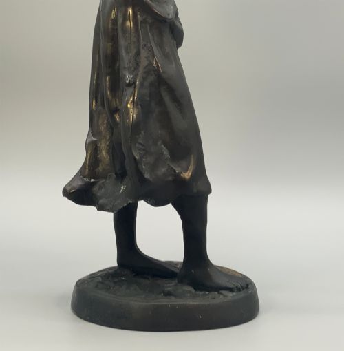 fig 10. An antique dark bronze sculpture of a young maiden wearing a draped apron dress, standing barefoot on a rounded integral base.
