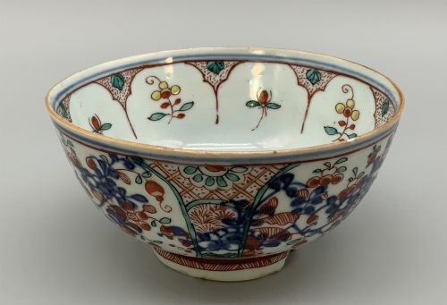 fig 4. An antique deep circular porcelain bowl featuring hand-painted Chinese Imari floral foliage and diaper pattern borders in blue, red, and green.