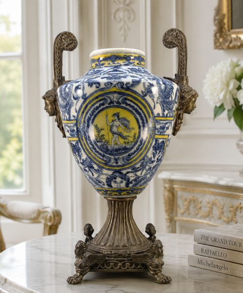 fig 1. A Renaissance Revival faience vase featuring blue and yellow glazed classical medallion artwork mounted on a cast bronze footed base with mask handles.