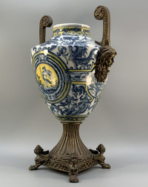 fig 5. A Renaissance Revival faience vase featuring blue and yellow glazed classical medallion artwork mounted on a cast bronze footed base with mask handles.