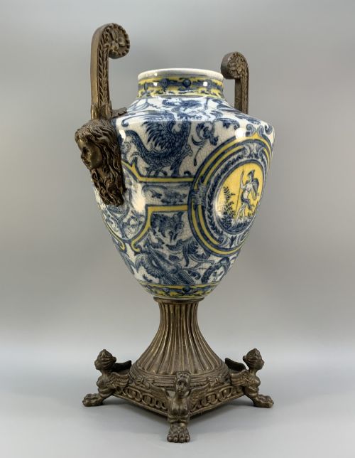 fig 9. A Renaissance Revival faience vase featuring blue and yellow glazed classical medallion artwork mounted on a cast bronze footed base with mask handles.