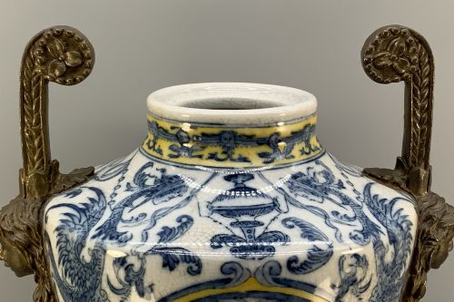 fig 12. A Renaissance Revival faience vase featuring blue and yellow glazed classical medallion artwork mounted on a cast bronze footed base with mask handles.
