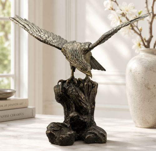 fig 1. A dark bronze sculpture depicting an eagle with outstretched wings perched on a rocky base.
