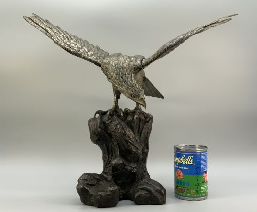 fig 2. A dark bronze sculpture depicting an eagle with outstretched wings perched on a rocky base.