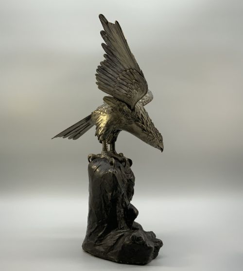 fig 4. A dark bronze sculpture depicting an eagle with outstretched wings perched on a rocky base.