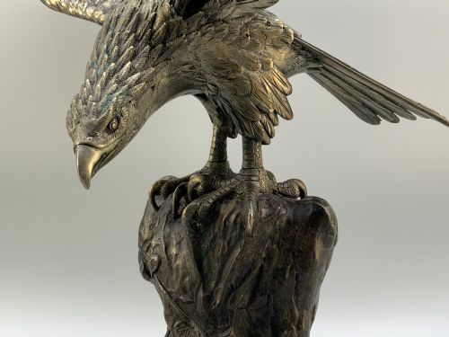fig 8. A dark bronze sculpture depicting an eagle with outstretched wings perched on a rocky base.