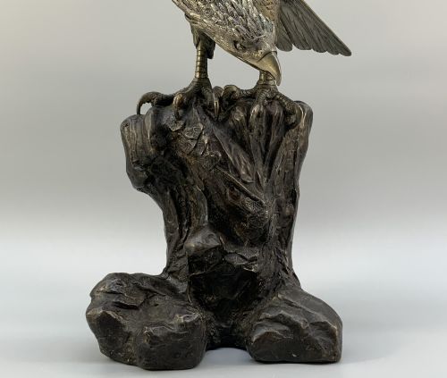 fig 9. A dark bronze sculpture depicting an eagle with outstretched wings perched on a rocky base.