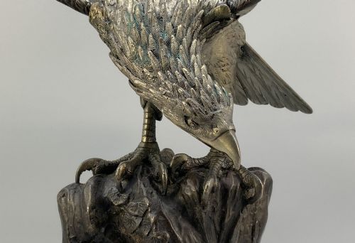 fig 10. A dark bronze sculpture depicting an eagle with outstretched wings perched on a rocky base.
