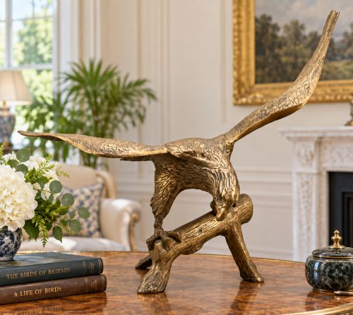 fig 1. A cast brass sculpture depicting an eagle with outstretched wings perched atop a detailed log branch.