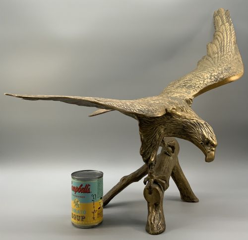 fig 2. A cast brass sculpture depicting an eagle with outstretched wings perched atop a detailed log branch.