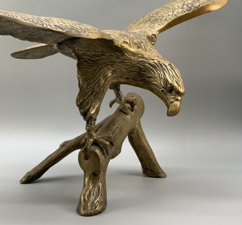fig 5. A cast brass sculpture depicting an eagle with outstretched wings perched atop a detailed log branch.
