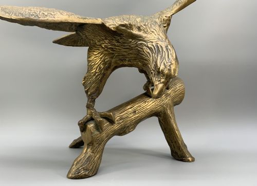 fig 6. A cast brass sculpture depicting an eagle with outstretched wings perched atop a detailed log branch.