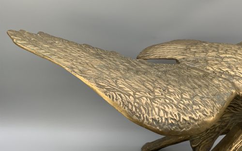 fig 7. A cast brass sculpture depicting an eagle with outstretched wings perched atop a detailed log branch.