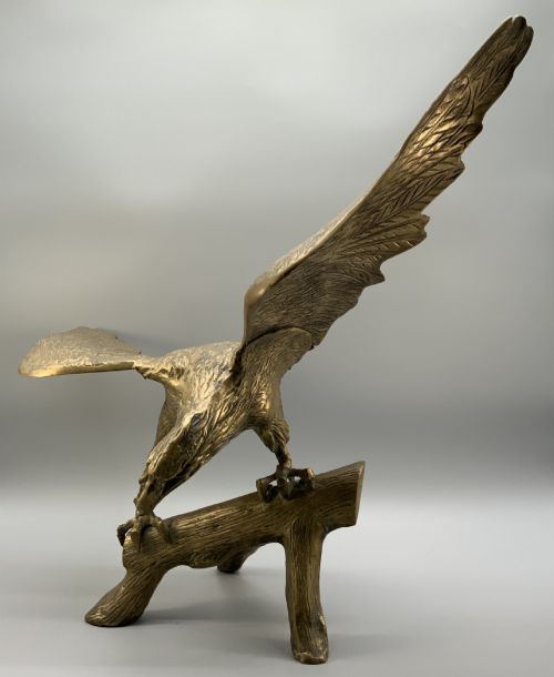 fig 8. A cast brass sculpture depicting an eagle with outstretched wings perched atop a detailed log branch.