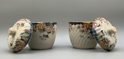 fig 5. A pair of 19th-century Japanese cream porcelain lidded jars featuring spiralled fluted bodies and hand-painted polychrome floral decoration with sculpted finials.